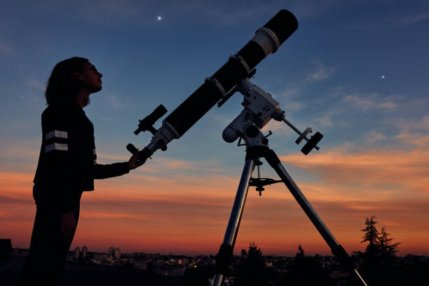 istock Girl with astronomical telescope stargazing under twilight sky. 1366642885