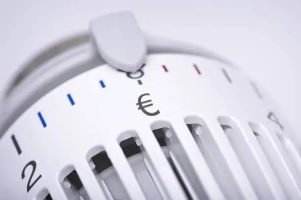 Thermostat of an heating radiator with Euro symbol, rising costs for heat and energy concept.