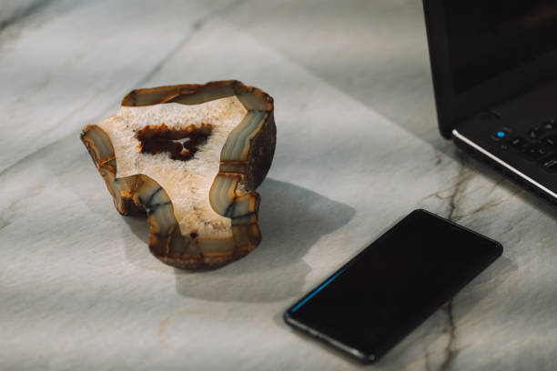 On the office table, a laptop mobile phone and a rare agate stone.