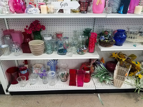 White shelves of used dishes and vases in a thrift store.