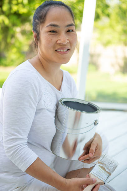 istock Smiling asian woman painting deck 1366646659