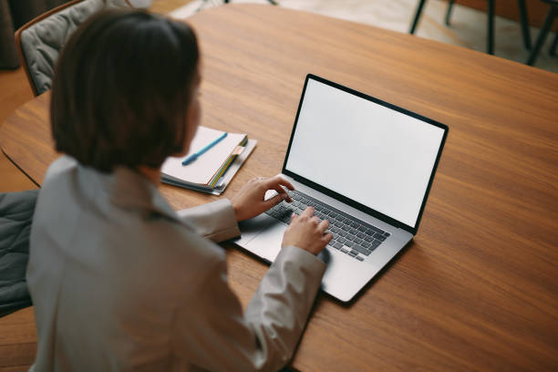 istock Business woman using laptop, looking at template blank screen, working online, sitting at office desk typing email 1366646661