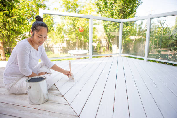 Smiling asian woman painting deck stock photo