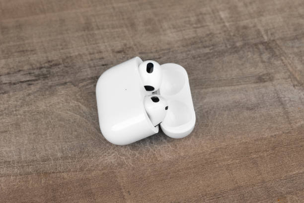 airpods 3 générations sur fond en bois. - third generation photos et images de collection