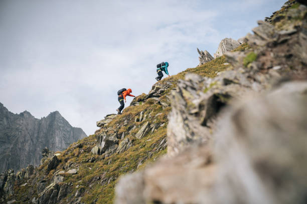 couple scramble up mountain ridge - steep imagens e fotografias de stock