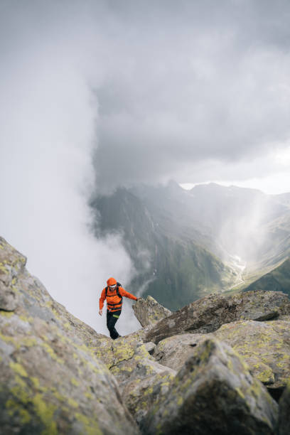 istock Mountaineer scrambles up mountain ridge 1366647443