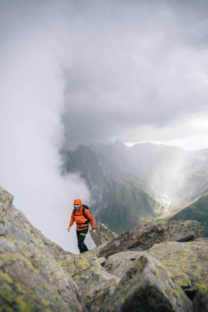 istock Mountaineer scrambles up mountain ridge 1366647453