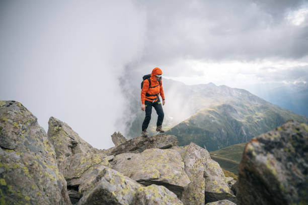 istock Mountaineer scrambles up mountain ridge 1366647500