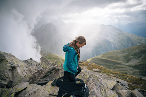 istock Woman mountaineer puts protective gear on, mountain ridge 1366648027