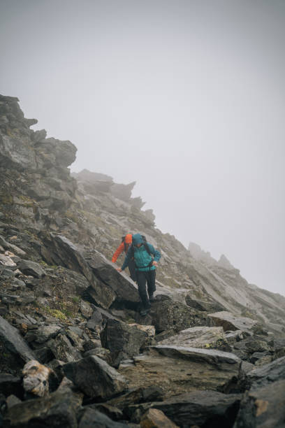 istock Mountaineers scramble up rocky slope 1366648116