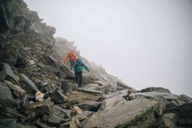 istock Mountaineers scramble up rocky slope 1366648117