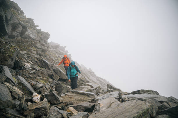 istock Mountaineers scramble up rocky slope 1366648126
