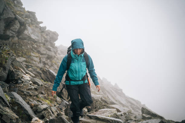 istock Woman mountaineer scrambles up mountain ridge 1366648127