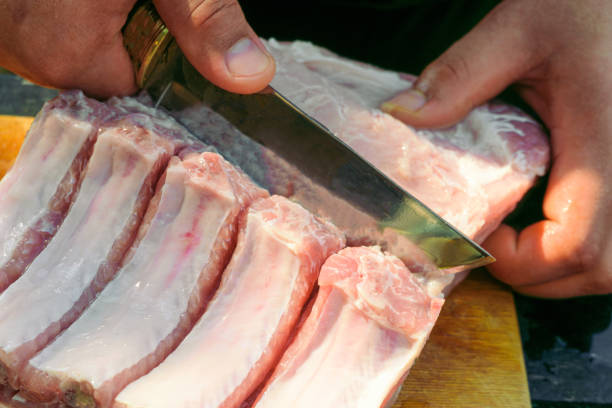 istock Cutting fresh meat with a knife. Pork ribs with meat. 1366649526
