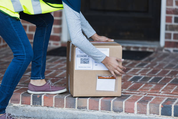 Unrecognizable delivery person picking up or dropping off package An unrecognizable female delivery person is either picking up or dropping off a package at a residence. doorstep stock pictures, royalty-free photos & images