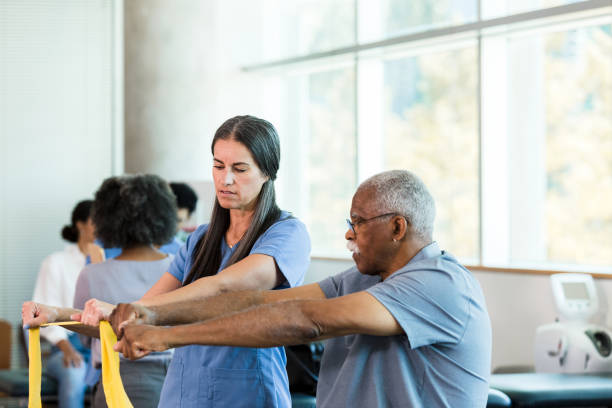 istock Physical therapist teaches senior man exercises with elastic band 1366650217