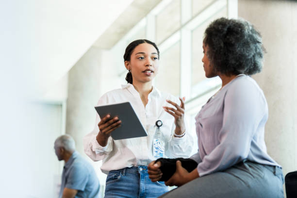 Physical therapist gestures while asking woman questions about injury The female young adult physical therapist gestures as she asks her mid adult patient questions about her injured wrist. alternative medicine stock pictures, royalty-free photos & images