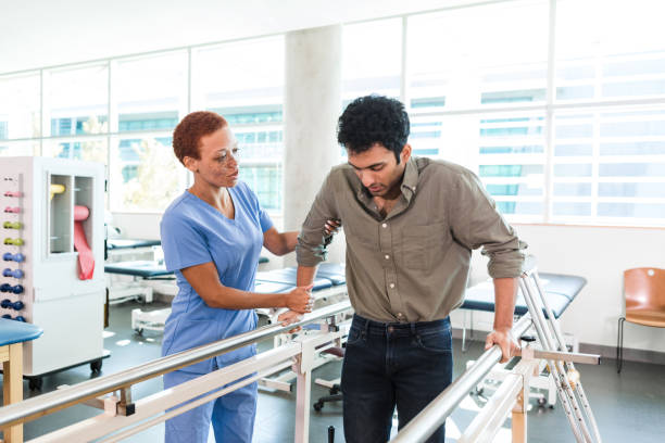 istock Occupational therapist works with young man on parallel bars 1366650752