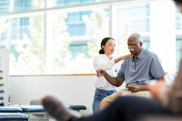 physical therapist examines senior man's shoulder - occupational therapy imagens e fotografias de stock