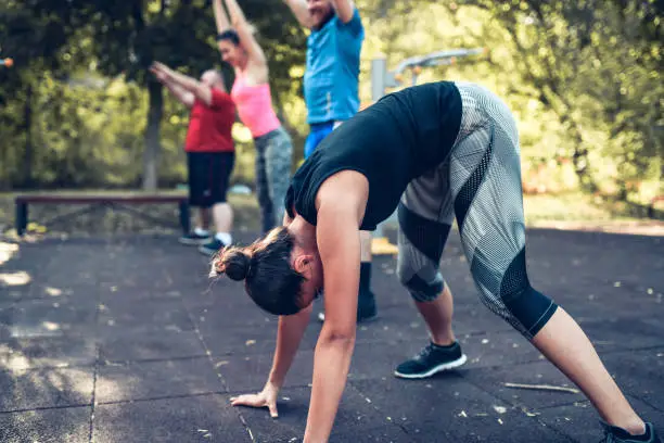 Athletic Female Doing Burpees With Friends Outside