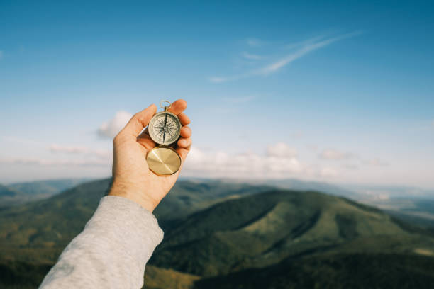 Vintage compass on a background of blue sky and mountains. stock photo