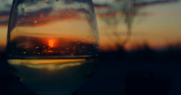 Abstract shot sunset glass shining golden hour in beautiful nature background. Abstract shot sunset glass shining golden hour in romantic nature landscape. Dinner date on dusk beach background. Beautiful majestic sunrise on beach environment near bonfire. Enjoy time concept. golden hour wine stock pictures, royalty-free photos & images