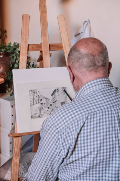istock Elderly man making a pencil drawing on an easel. Old people activities concept. 1366655569