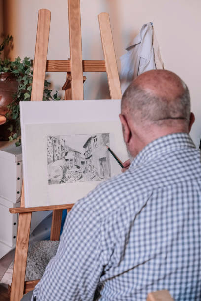 istock Elderly man making a pencil drawing on an easel. Old people activities concept. 1366655610
