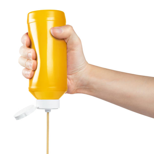 istock Hand squeezing mustard out of a plastic bottle on white 1366658282