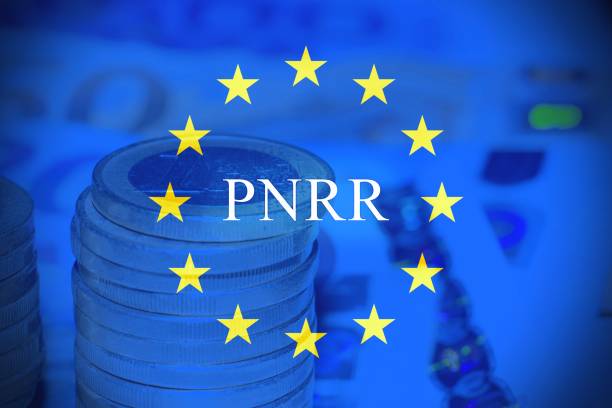 primer plano de una pila de monedas de 1 euro con billetes en euros y bandera europea como fondo con el texto "pnrr". - usa european union flag trading europe fotografías e imágenes de stock