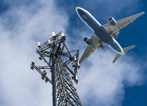 5G Cell phone or mobile service tower with aircraft approaching to land stock photo