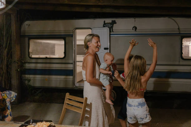 Campervan summer nights Photo of a mother and her children having fun outside their campervan; enjoying the warm summer night at a remote location, far from the city. baby boy dancing with his mommy stock pictures, royalty-free photos & images
