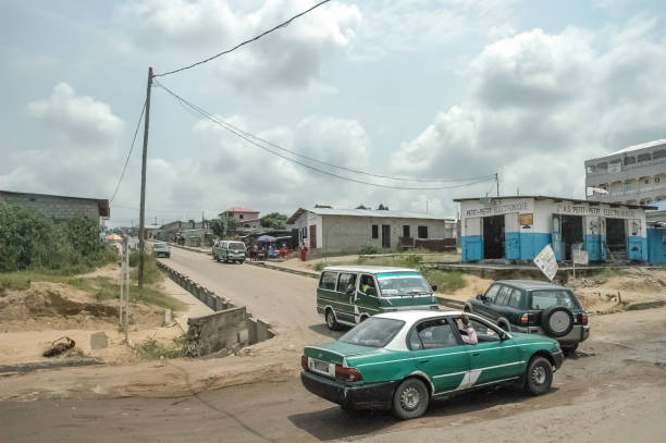 Crossroad in African urban area with potholes, green taxi car, taxi bus on hot cloudy day. stock photo