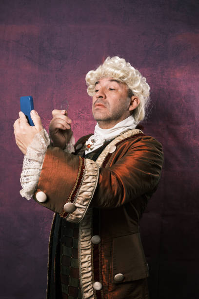 istock Serious man in classical renaissance clothes using an old monocle to see the mobile phone screen. 1366662918