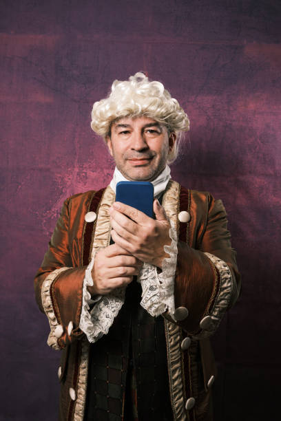 istock Adult man in classical medieval clothing using a mobile phone while standing on an isolated background. 1366662965