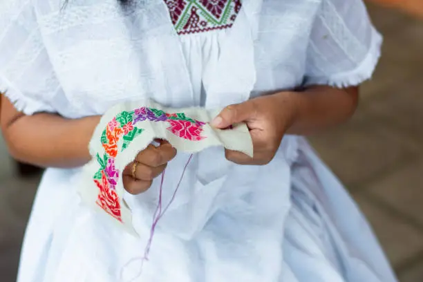 Unrecognizable mexican woman sewing traditional knitted fabric