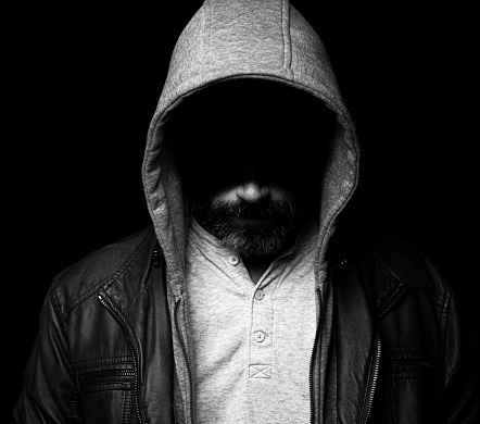 Bearded man wearing a hood and leather jacket with eyes hidden