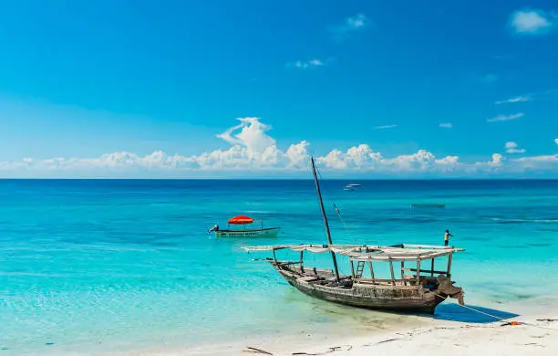 Wooden fishing ship on the white sand beach on low tide, Indian ocean. Zanzibar, Tanzania.