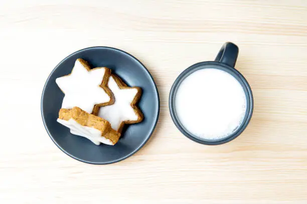 Plate of cinnamon star cookies and a cup of milk left out for Santa on a Christmas eve.