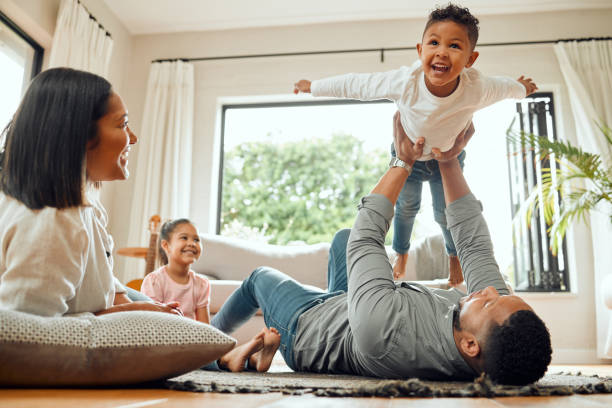 自宅のラウンジフロアで一緒に遊ぶ若い家族のショット - 幸福 ストックフォトと画像