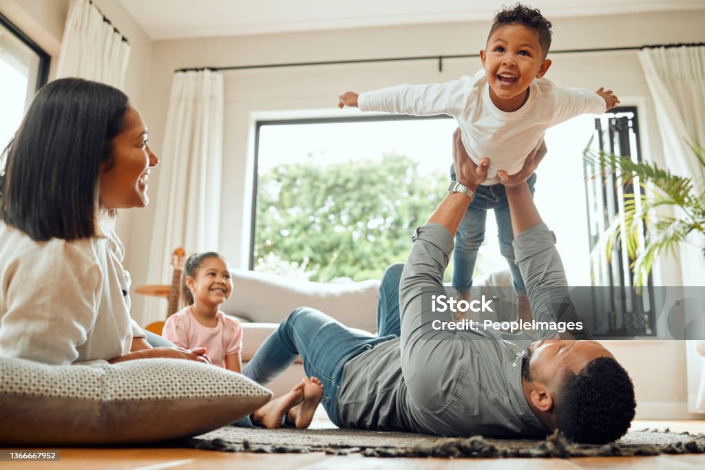 Shot of a young family playing together on the lounge floor at home Who would want more? Family Stock Photo