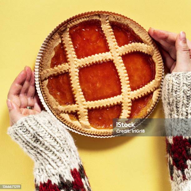 Italian Crostat Pie With Apricot Jam On A Yellow Background And Female Hands In A Warm Woolen Sweater With An Ornament Stock Photo - Download Image Now