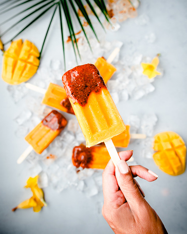 Close up of hand holding  a mango popsicle