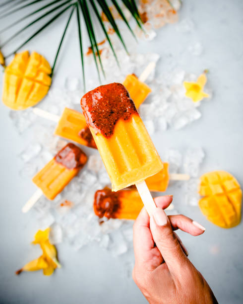 Close up of hand holding  a mango popsicle stock photo