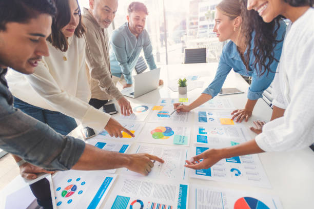 istock Multi racial group of people working with Paperwork on a board room table at a business presentation or seminar. 1366672571