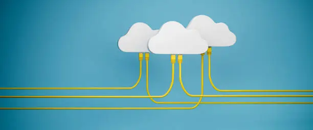 Photo of Cloud Computing Concept - Three clouds with plugged in Ethernet Cables. Blue background. Web banner format