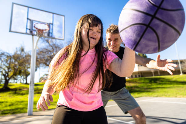 niña con síndrome de down jugando al baloncesto con su familia - bouncing ball family playing fotografías e imágenes de stock