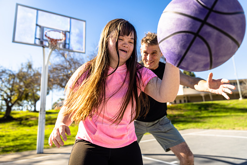 A girl who has Down’s Syndrome playing basketball with her family