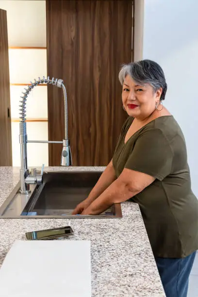 Photo of Older woman with brown hair washing in the kitchen