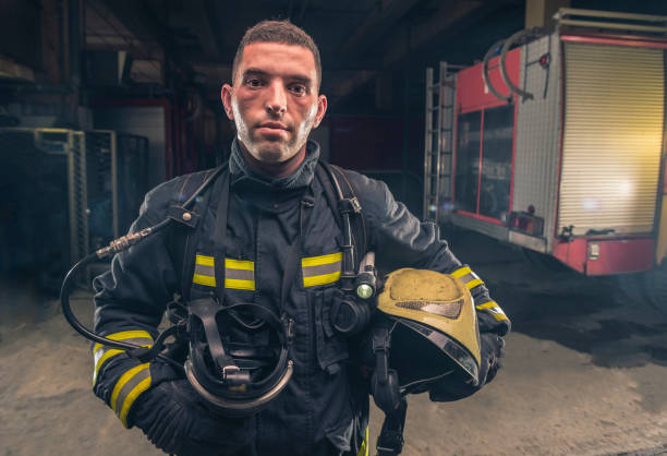 緊急サービスの準備ができてヘルメットを保持している消防士の投票率を身に着けている消防士の肖像画。 - turnouts ストックフォトと画像
